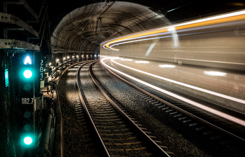 Train tunnel with green signal light - train travelling through long exposure shot with yellow and white light streaking to show movement