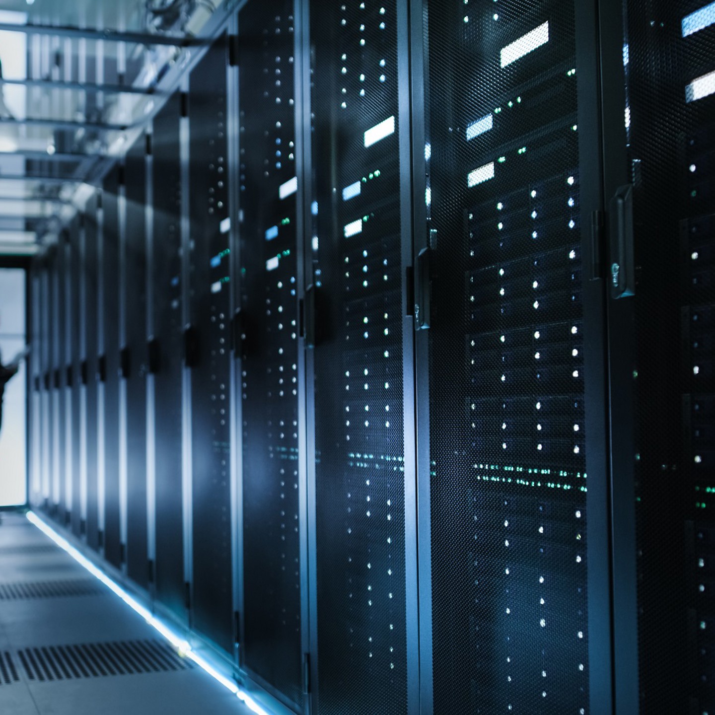 Man looking at data servers in a large server storage room