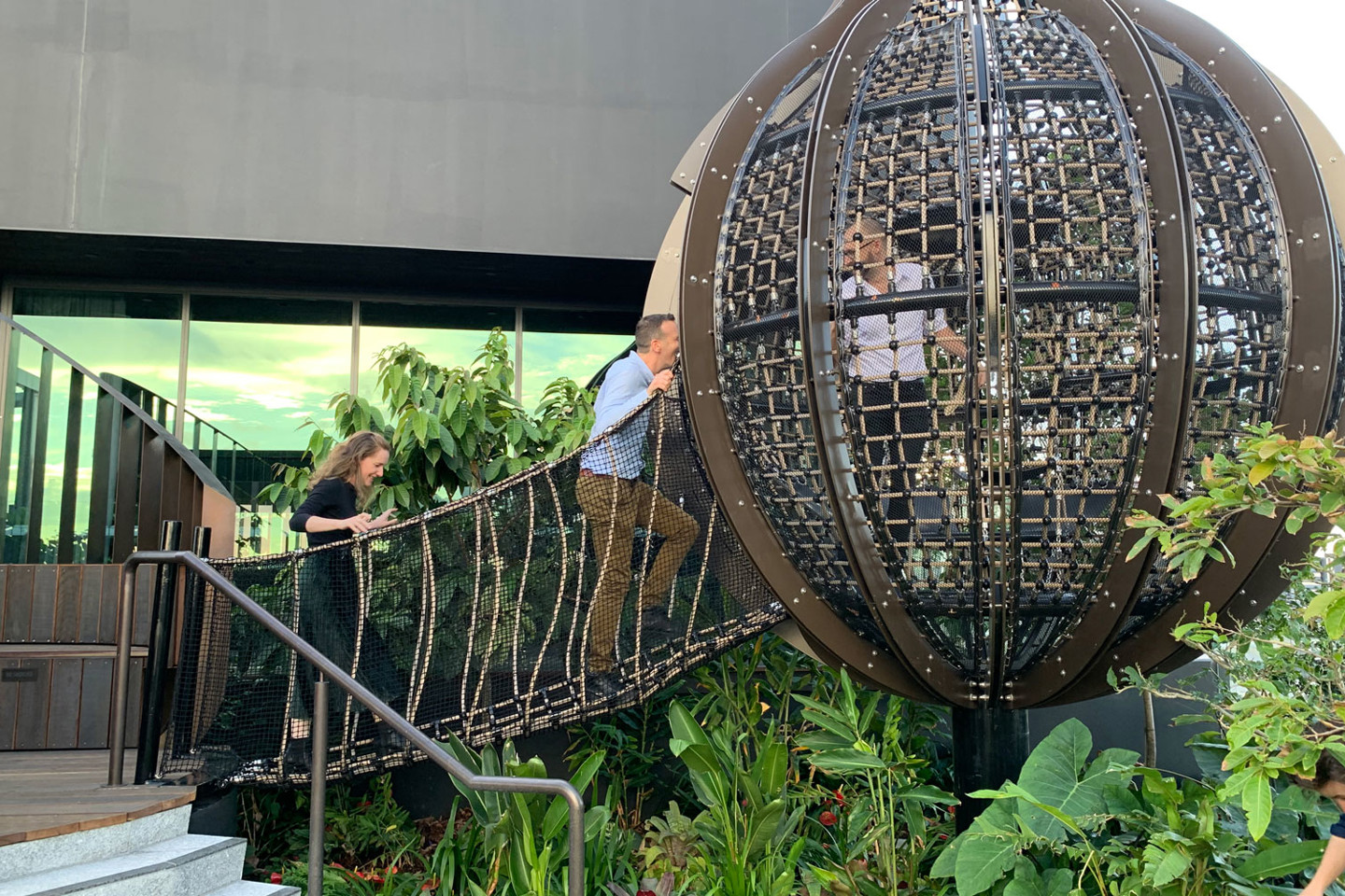 RPS landscape architects walk over a draw bridge which leads to a hanging dome over a lush garden.  