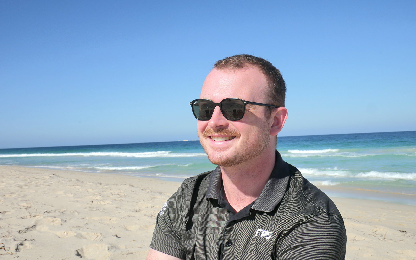 RPS scientist Ciaran Carolan smiles against the backdrop of a sunny Perth beach 