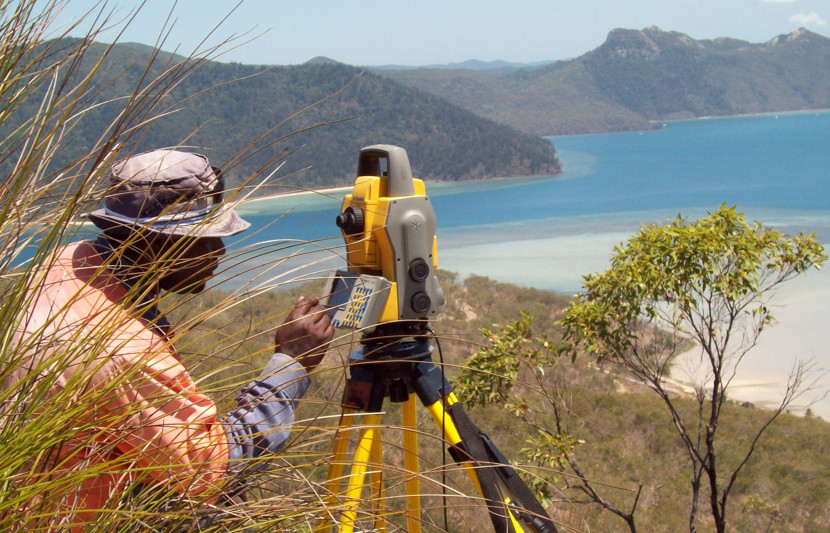 RPS surveyor takes a reading in scrub overlooking and idyllic ocean setting. 